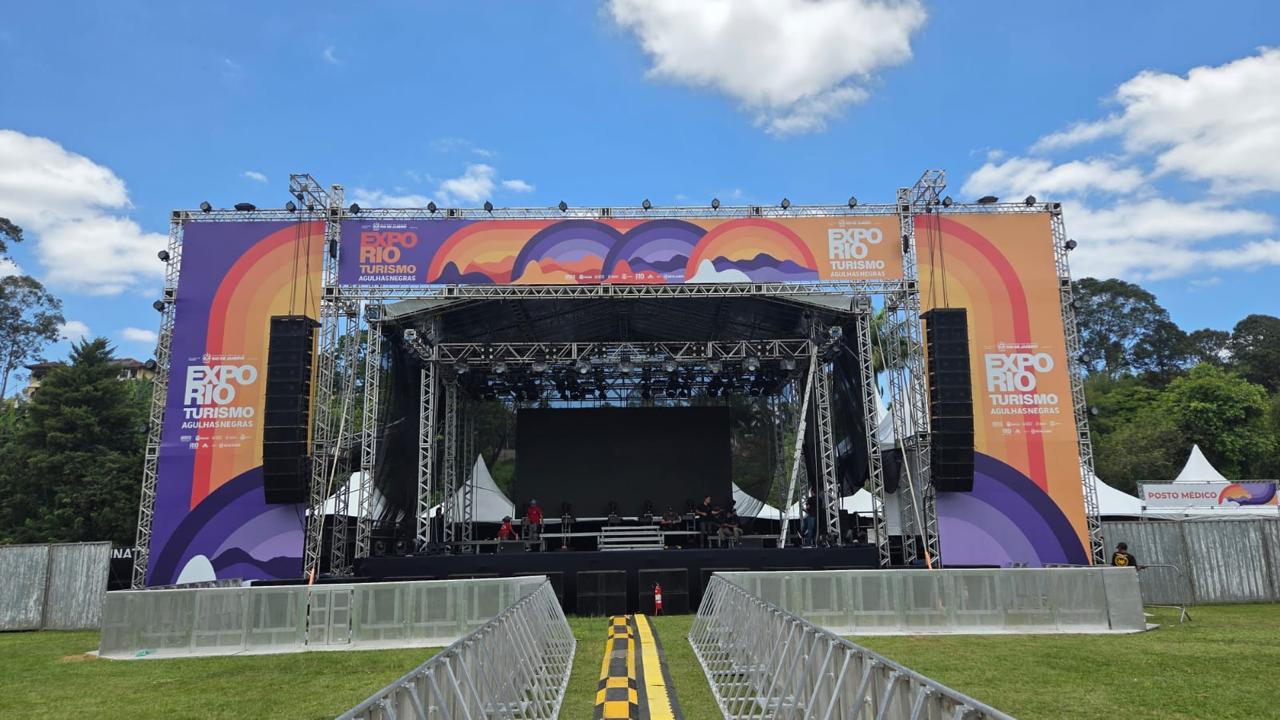 Palco principal com cobertura em duas águas, grid de iluminação e lona impressa montado pela Vitória Brasil Eventos